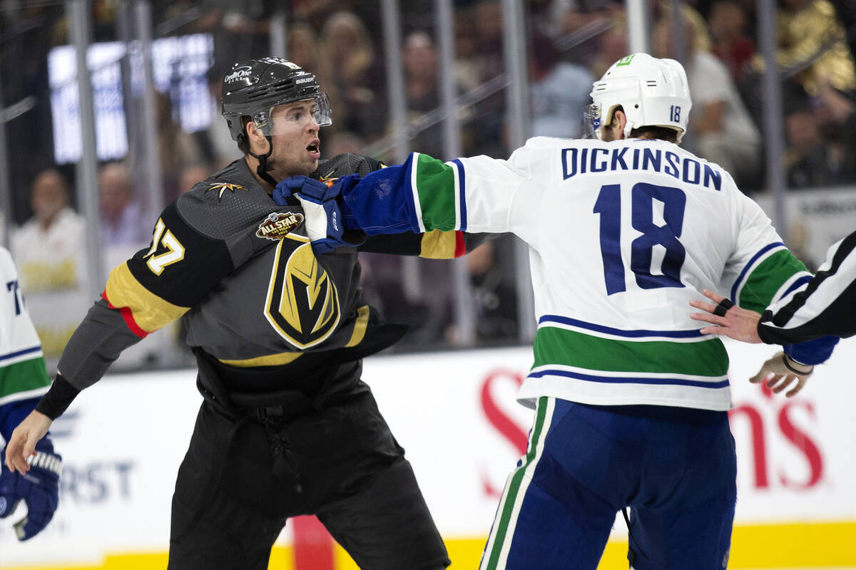 Golden Knights defenseman Ben Hutton (17) and Canucks center Jason Dickinson (18) fight during ...