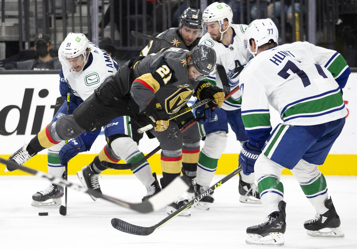 Golden Knights center Brett Howden (21) fights for the puck with Canucks left wing Juho Lammik ...
