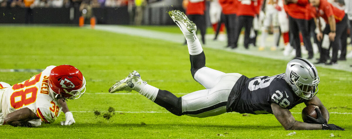 Raiders running back Josh Jacobs (28) dives for yards after taken down by Kansas City Chiefs co ...