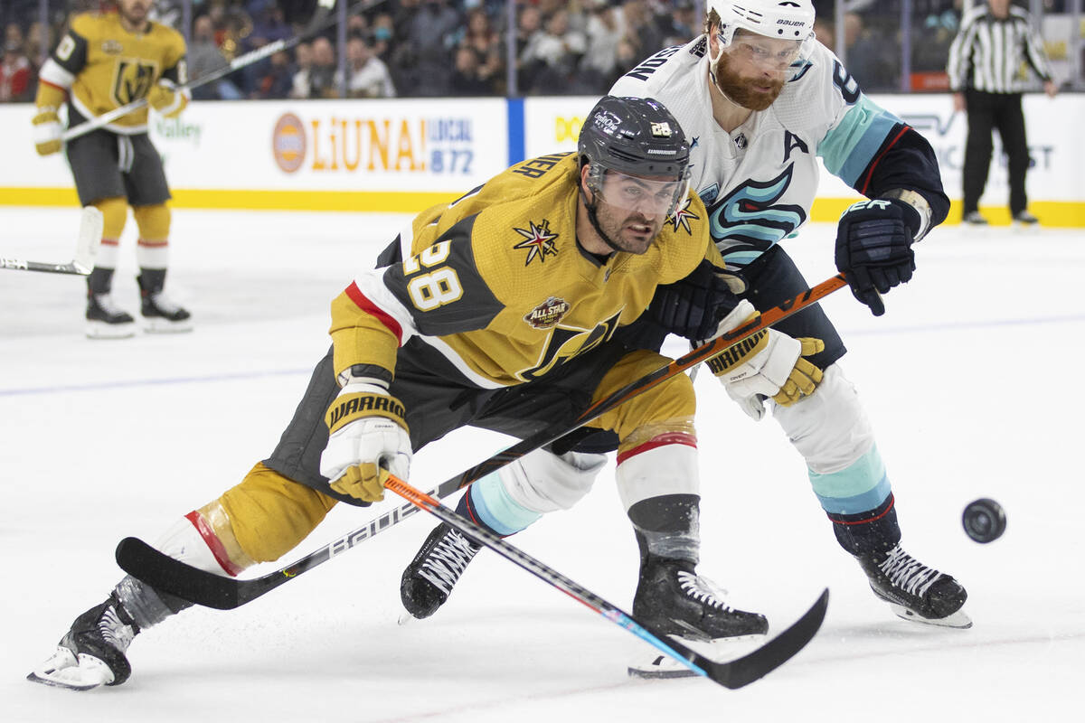 Vegas Golden Knights left wing William Carrier (28) fights for a loose puck with Seattle Kraken ...