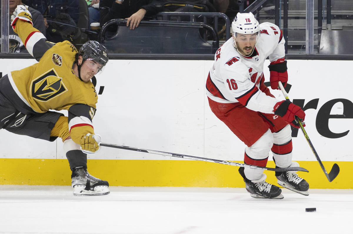 Golden Knights defenseman Dylan Coghlan (52) fights for a loose puck with Carolina Hurricanes c ...