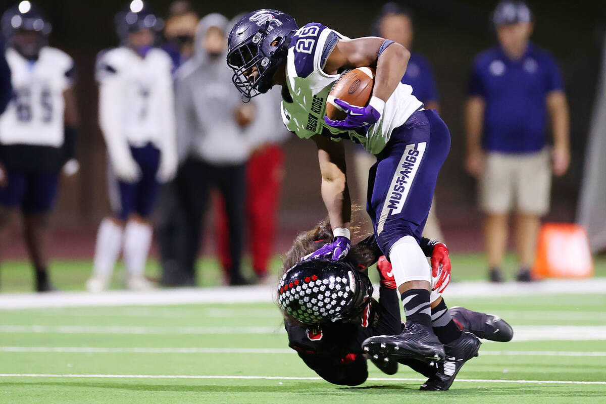 Shadow Ridge's Jaquieze Holland (25) stiff arms Las Vegas' Kawika Lopez (8) during a run in the ...