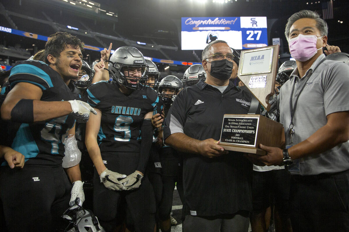 Silverado head coach Alejandro Ostolaza accepts Class 4A football state championship trophy aft ...