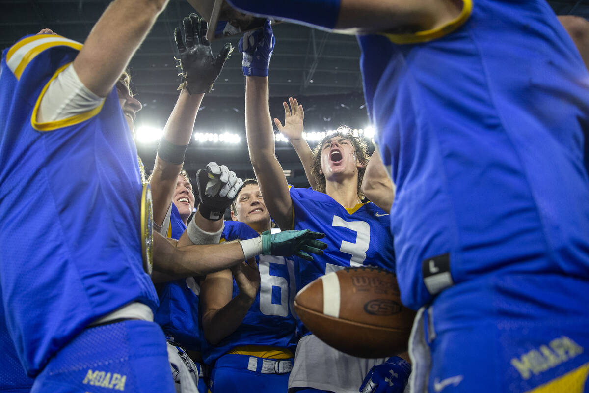 Moapa Valley players including Dustin Gordon (3) and Clay Whipple (60) cheer while holding up t ...