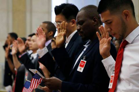 Participants take the oath of allegiance during a naturalization ceremony for 70 citizenship ca ...