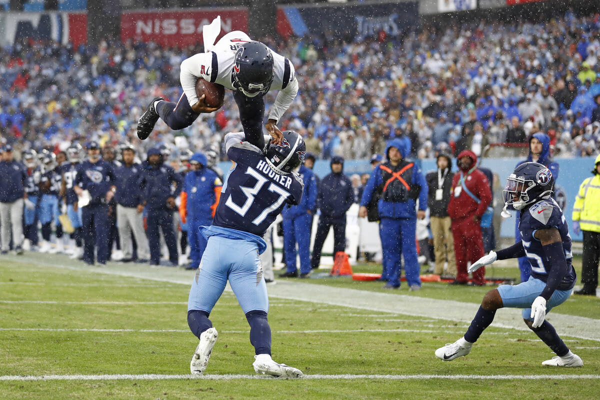 Houston Texans quarterback Tyrod Taylor, top, leaps over Tennessee Titans safety Amani Hooker ( ...