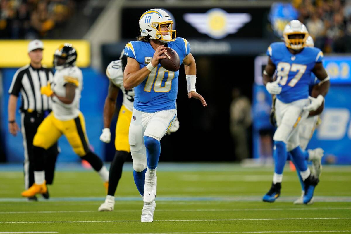 Los Angeles Chargers quarterback Justin Herbert runs with the ball during the first half of an ...