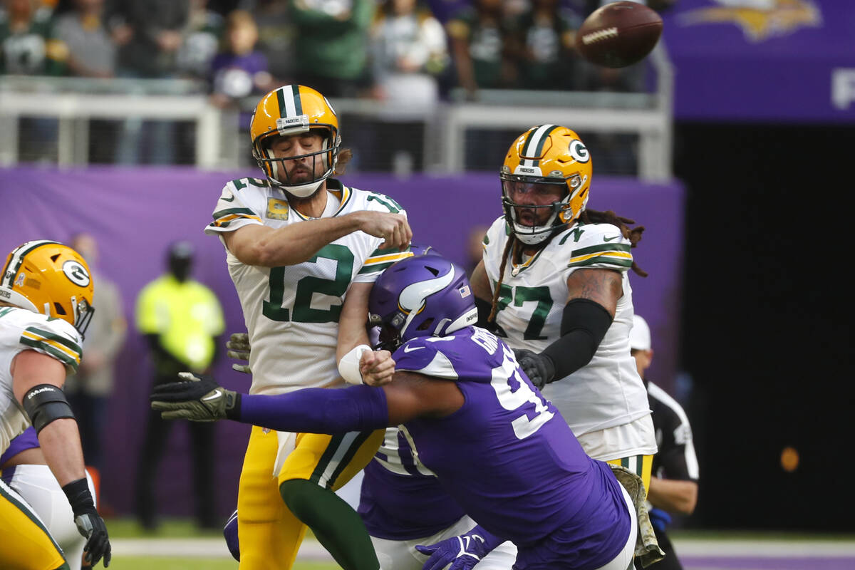 Green Bay Packers quarterback Aaron Rodgers (12) passes as he is hit by Minnesota Vikings defen ...