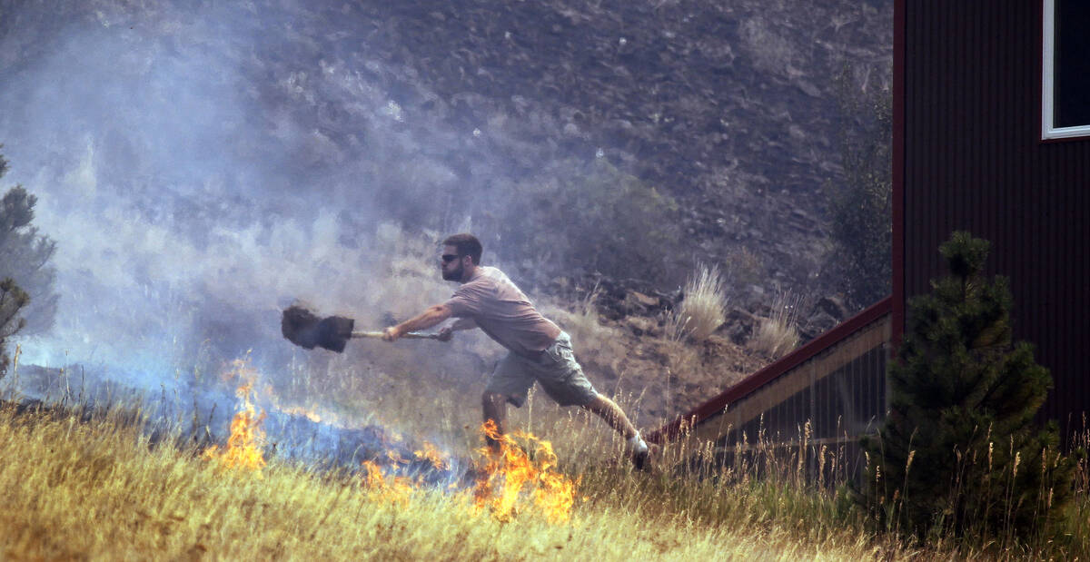 In this Aug. 14, 2012 file photo a man tosses dirt on a fire as he tries to save his home on Be ...