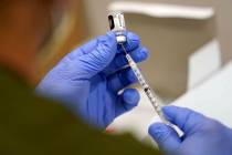 A healthcare worker fills a syringe with the Pfizer COVID-19 vaccine at Jackson Memorial Hospit ...
