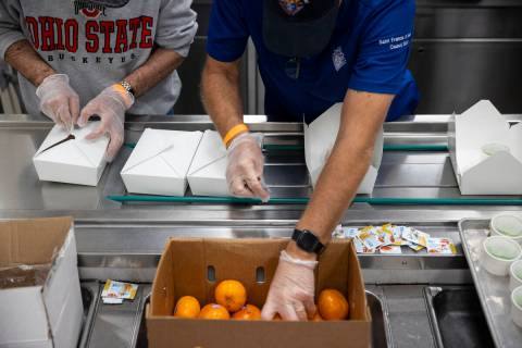Volunteers package after school lunches at the Three Square North Campus in Las Vegas, Thursday ...