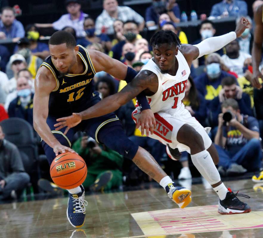 Michigan Wolverines guard DeVante' Jones (12) keeps a ball away from UNLV Rebels guard Michael ...