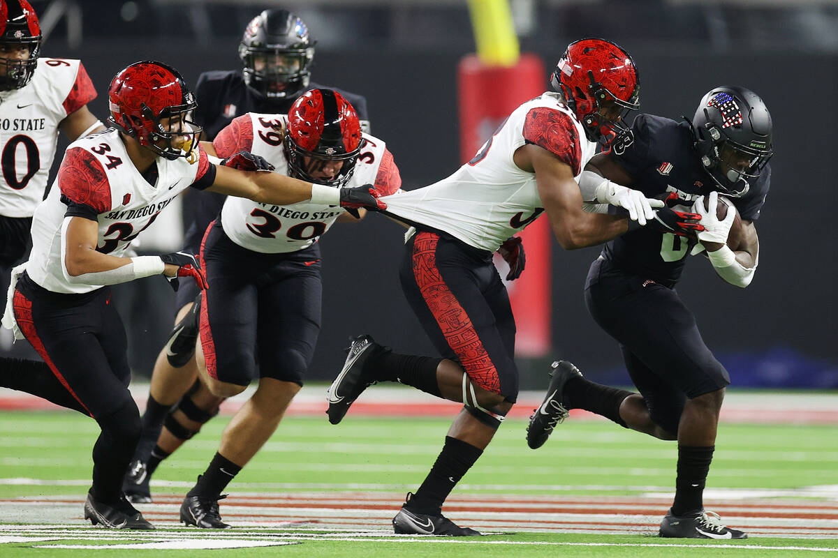 UNLV Rebels running back Charles Williams (8) runs the ball under pressure from San Diego State ...