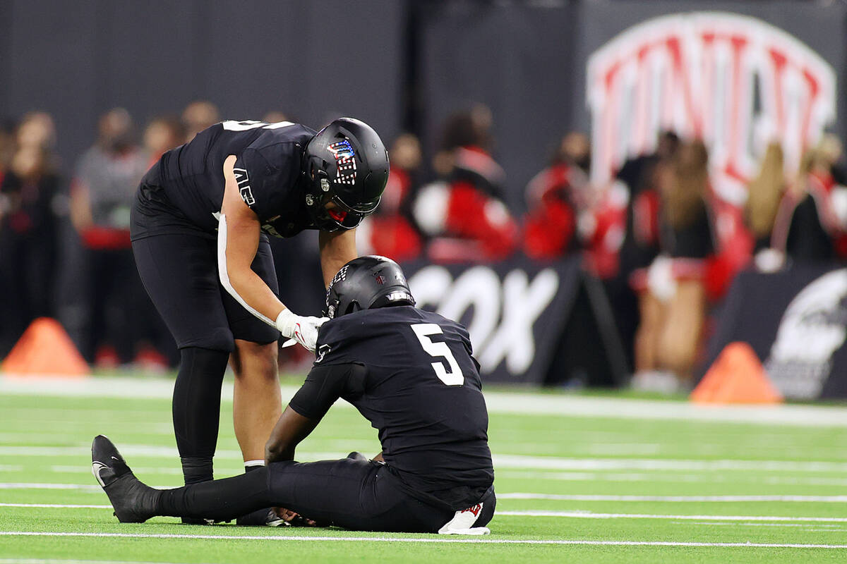 UNLV Rebels tight end Giovanni Fauolo Sr. (45) checks on quarterback Justin Rogers (5) after he ...