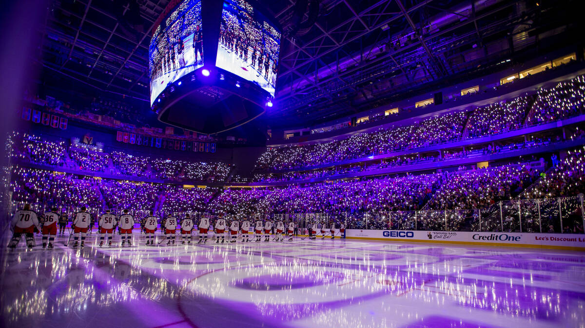 The arena is lit up by phone flashlights in honor of cancer victims before the first period of ...