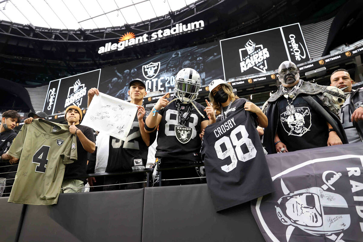 Fans pose for a photo before the start of an NFL football game between the Las Vegas Raiders an ...