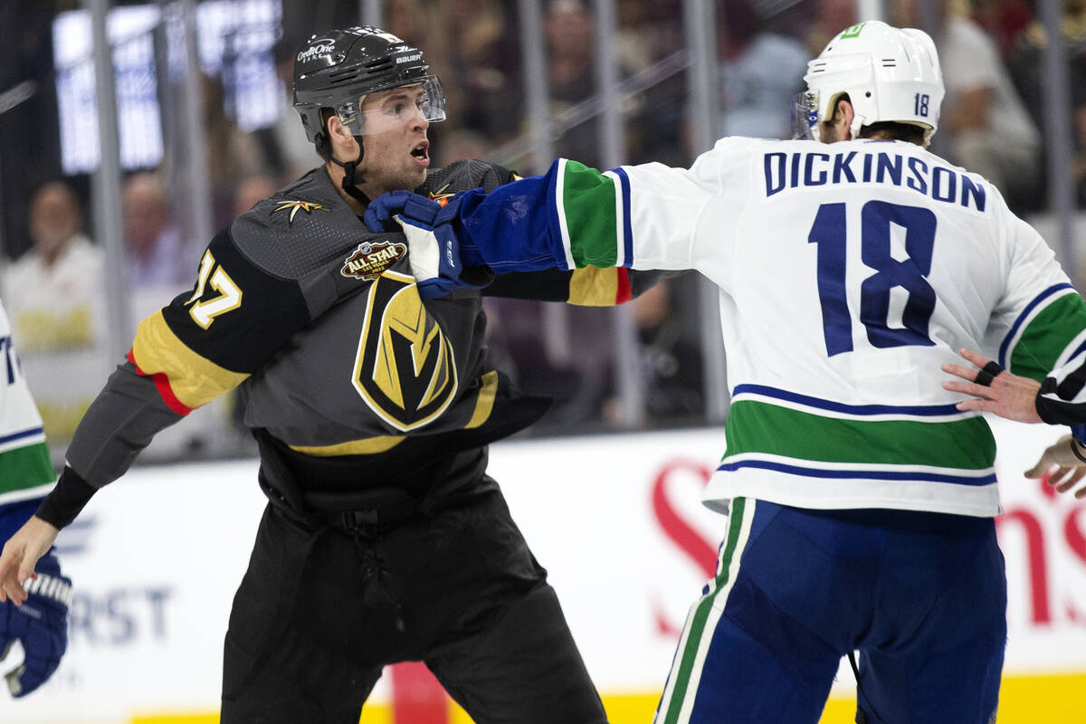 Golden Knights defenseman Ben Hutton (17) and Canucks center Jason Dickinson (18) fight during ...