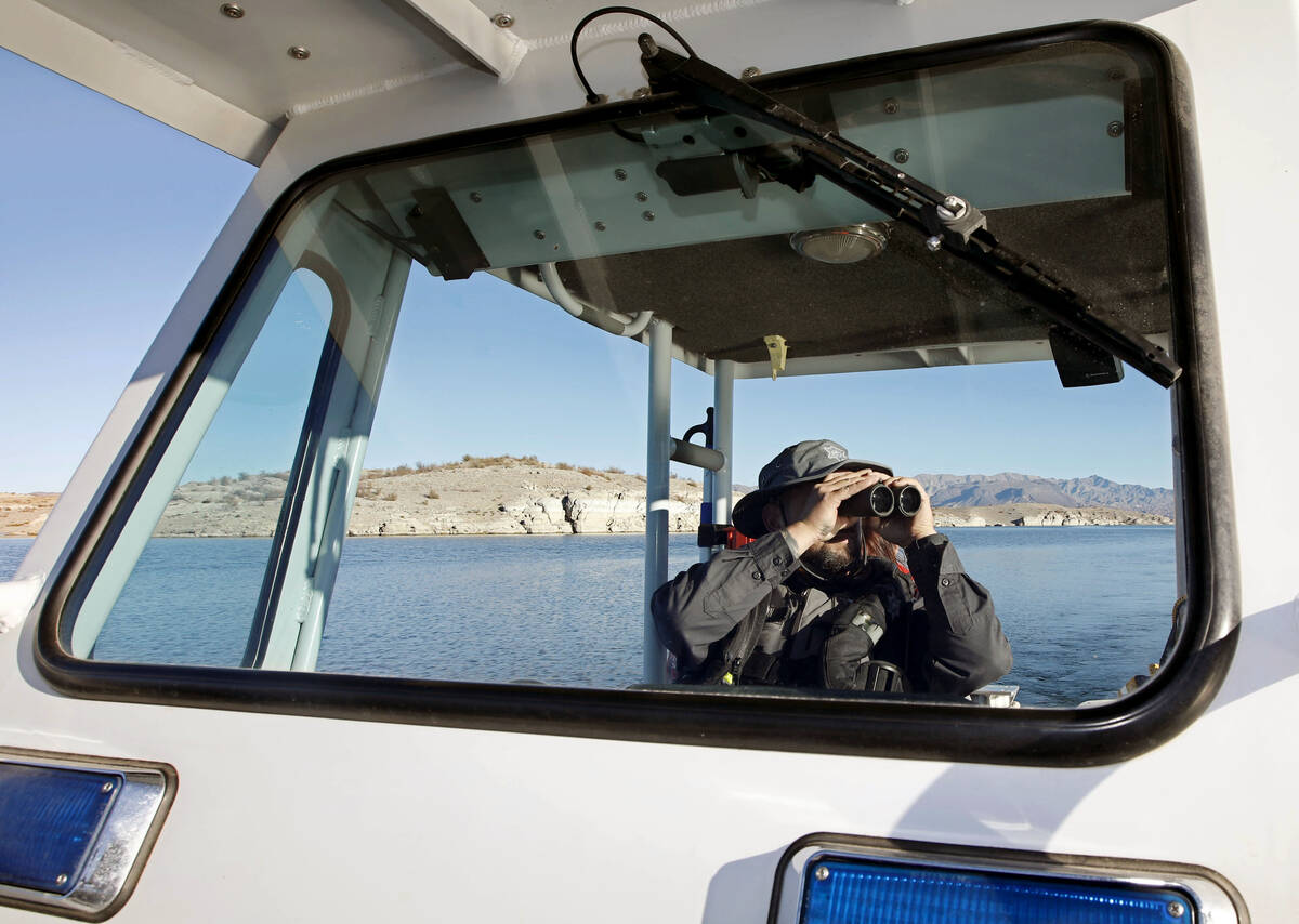 Sean Flynn, Nevada Department of Wildlife game warden, uses binoculars while he patrols Lake Me ...