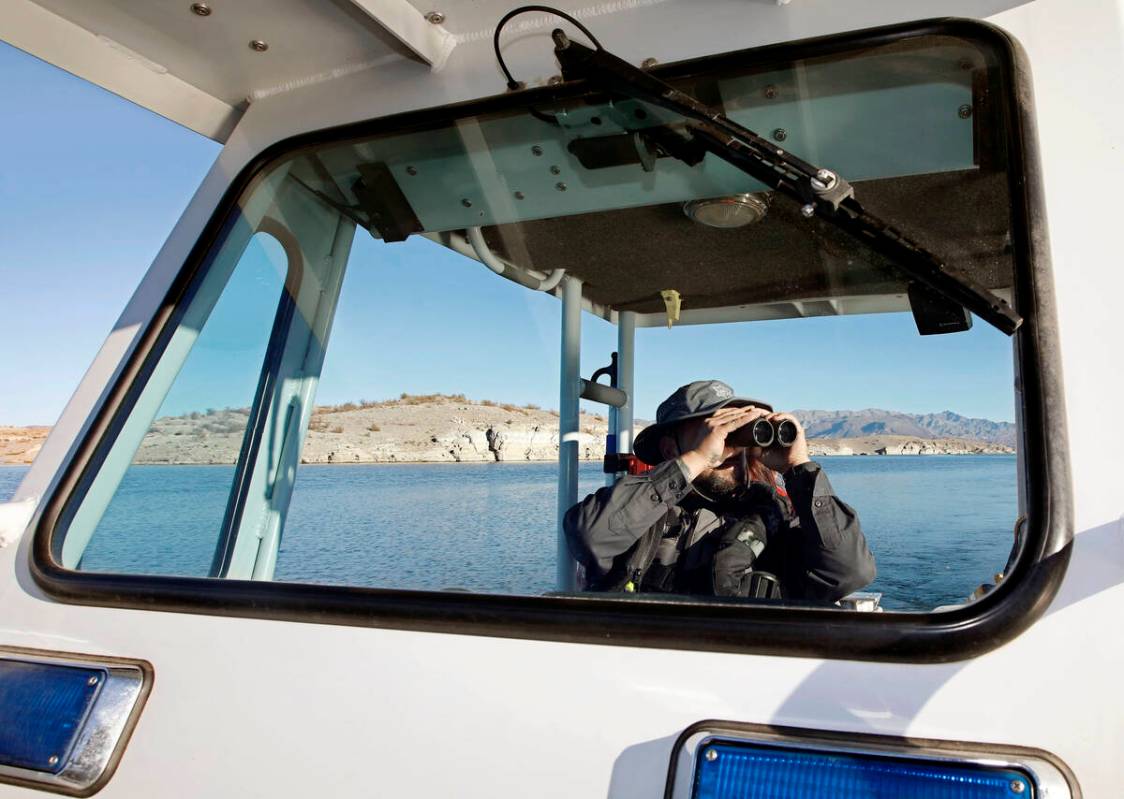 Sean Flynn, Nevada Department of Wildlife game warden, uses binoculars while he patrols Lake Me ...