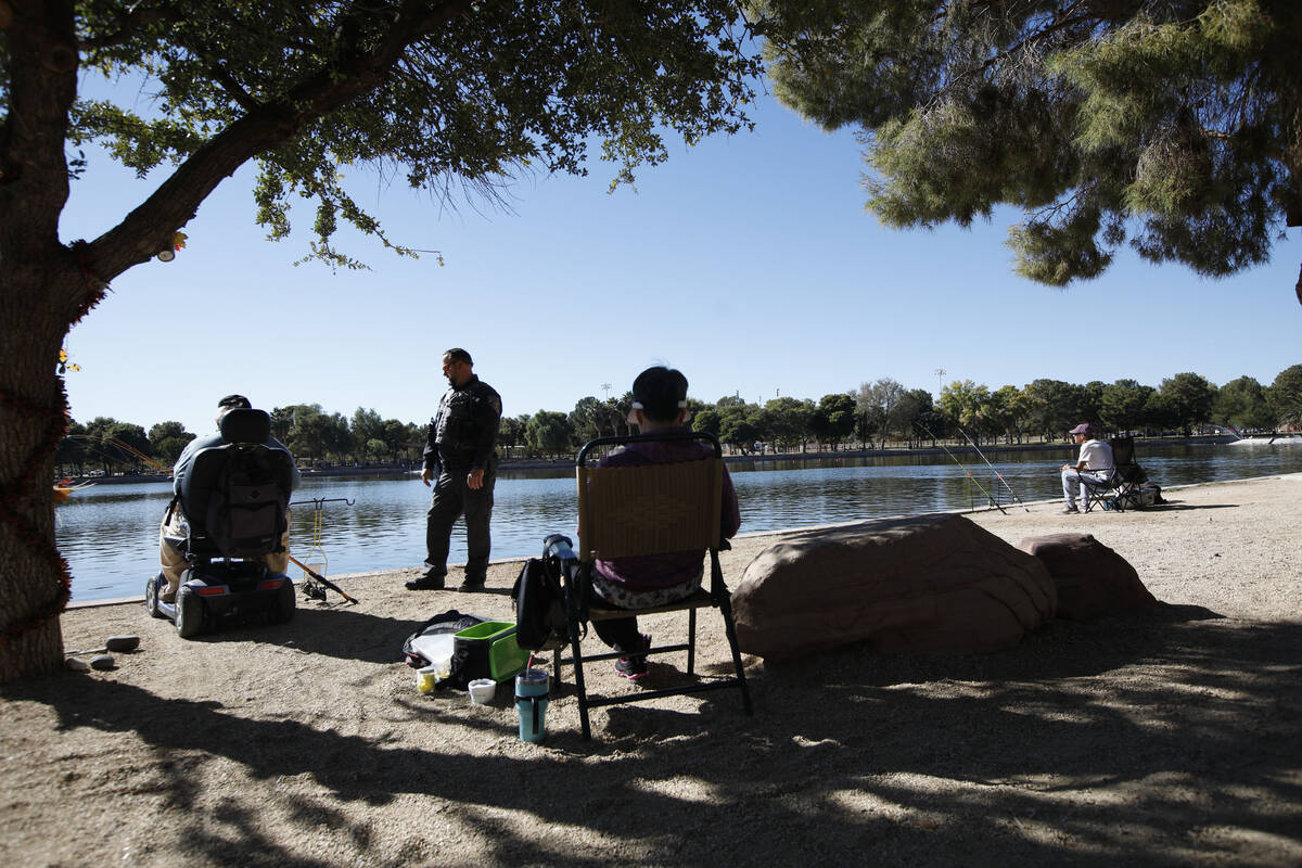 Sean Flynn, Nevada Department of Wildlife game warden, center, talks with a fisherman while he ...