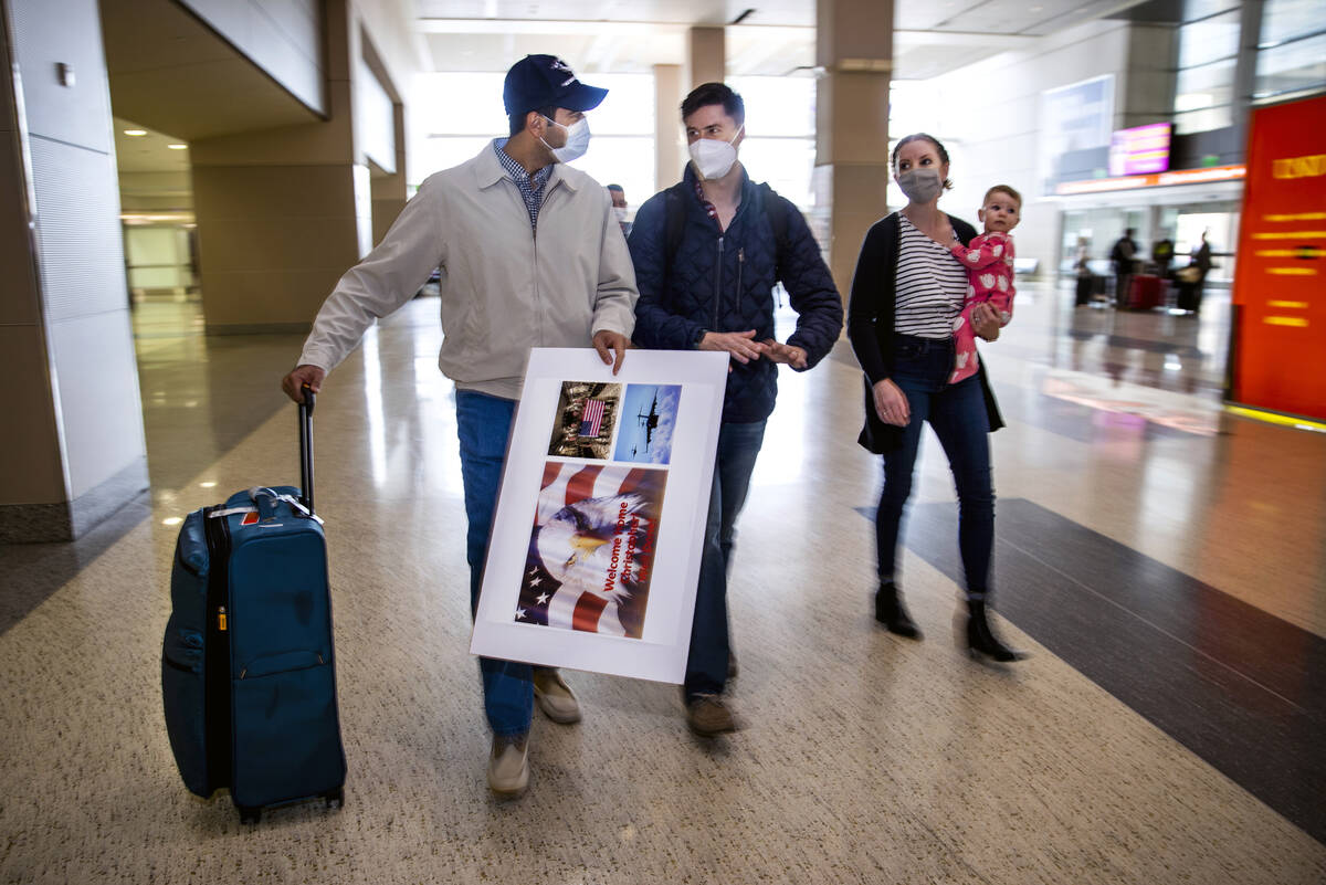 Afghan evacuee Benny walks through the terminal beside Christopher and Kristin Hoffman with dau ...