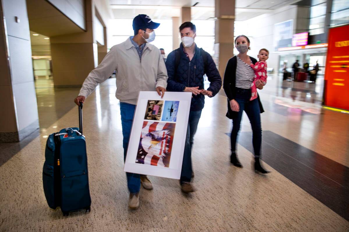 Afghan evacuee Benny walks through the terminal beside Christopher and Kristin Hoffman with dau ...