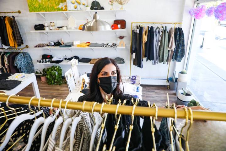 Emily Johnson, owner of the boutique clothing store For the love, LV, adjusts clothes on a rack ...