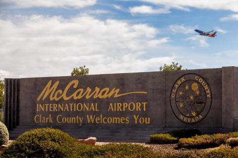 Sign for McCarran International Airport with plane taking off above at Tropicana Avenue and Kov ...