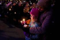 A small child takes part in a candle light vigil in downtown Waukesha, Wis., Monday, Nov. 22, 2 ...