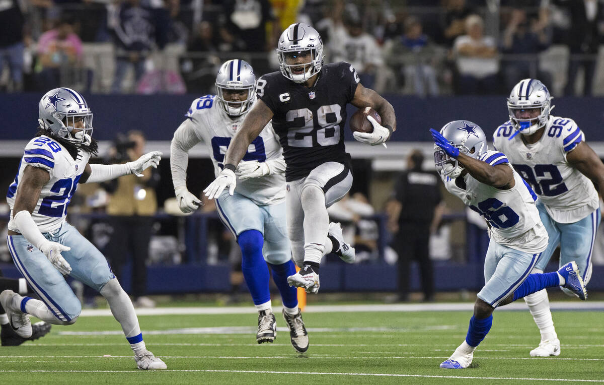 Raiders running back Josh Jacobs (28) leaps through a hole for a big run past Dallas Cowboys s ...