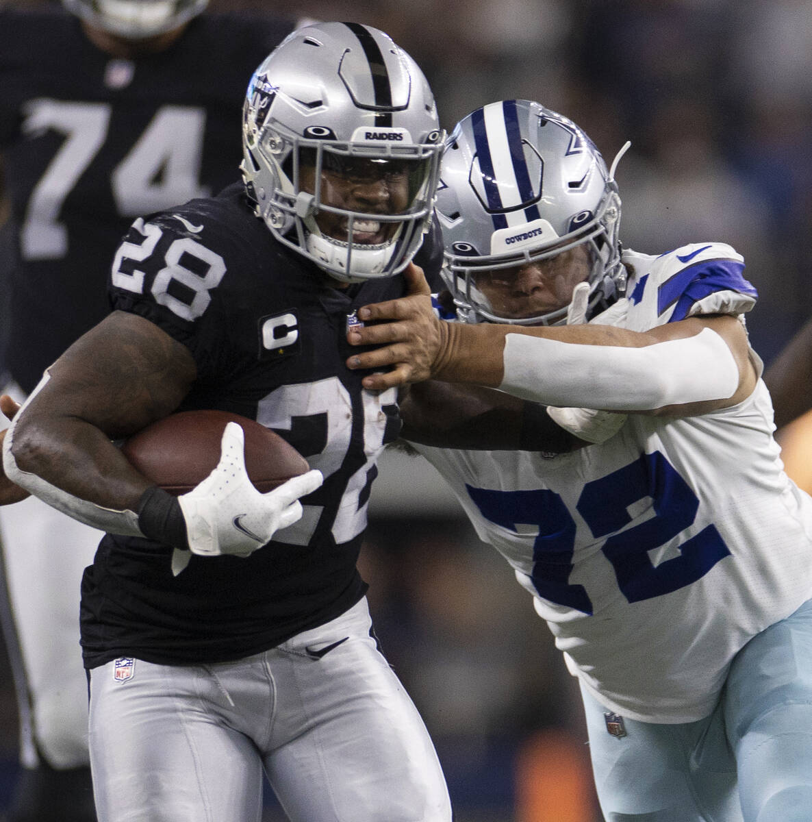 Raiders running back Josh Jacobs (28) fights for extra yardage against Dallas Cowboys defensive ...