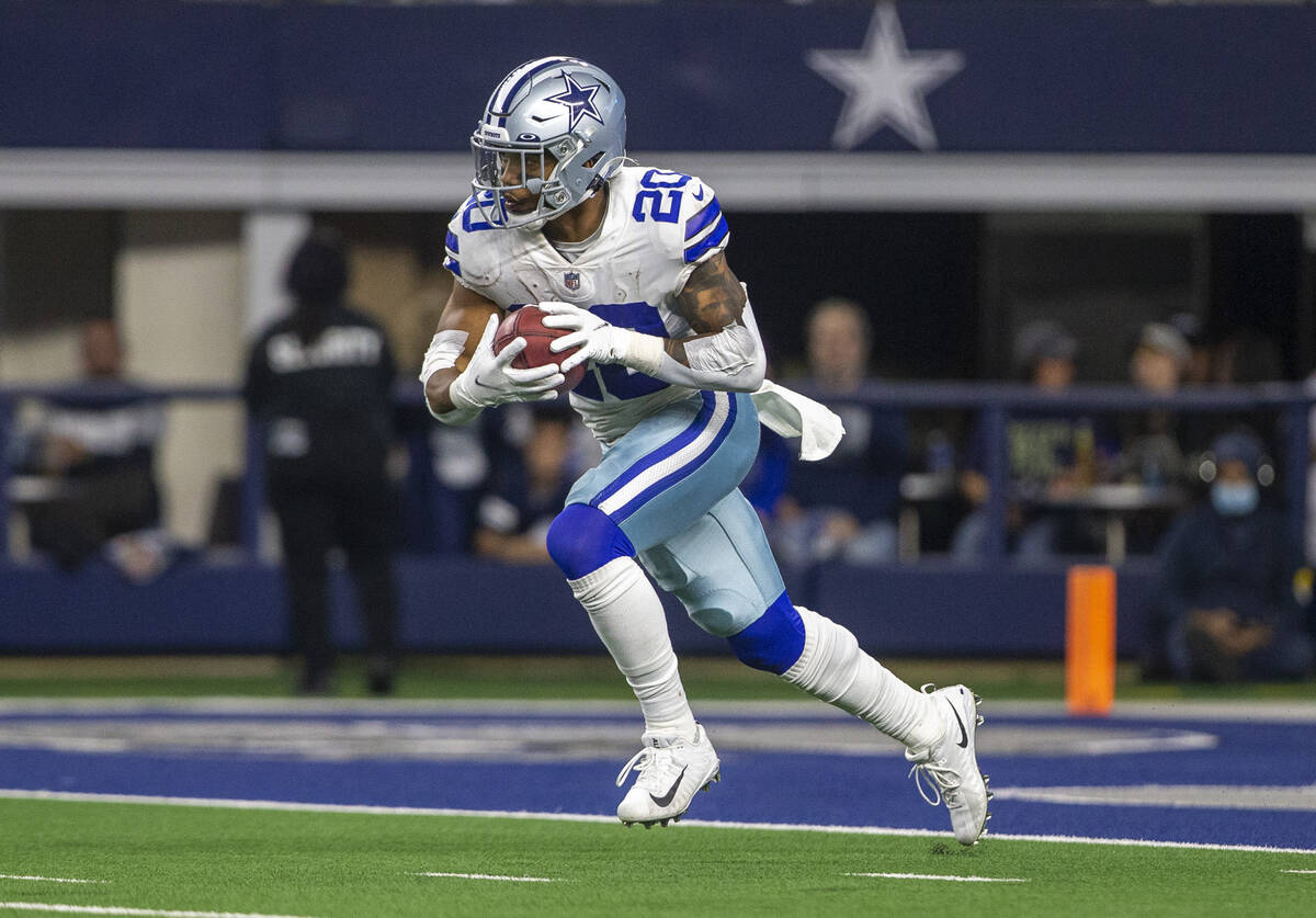 Dallas Cowboys running back Tony Pollard (20) looks for room to run after fielding a kickoff, w ...
