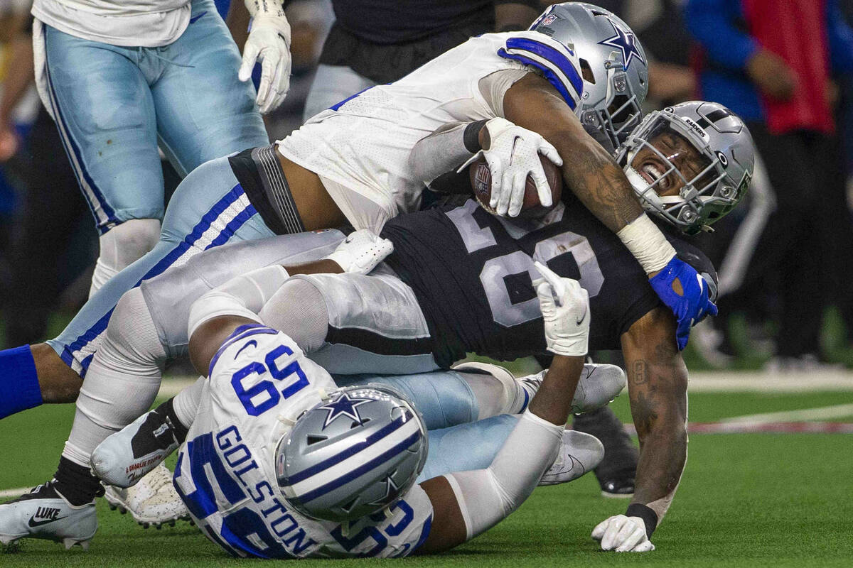 Raiders running back Josh Jacobs (28) grimaces as he is tackled by Dallas Cowboys safety Malik ...