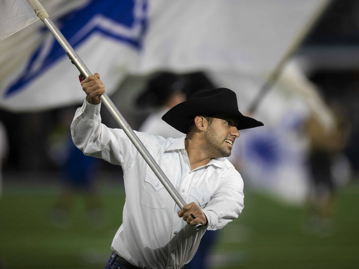 Men wave flags on the field before the start of an NFL football game between the Raiders and th ...