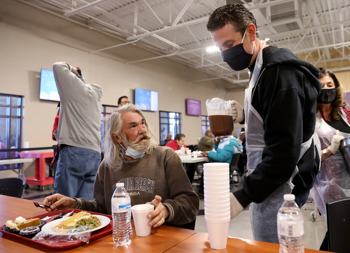 Richard Arlen Curry Jr. eats a free Thanksgiving meal as Max Berkley serves hot chocolate in th ...