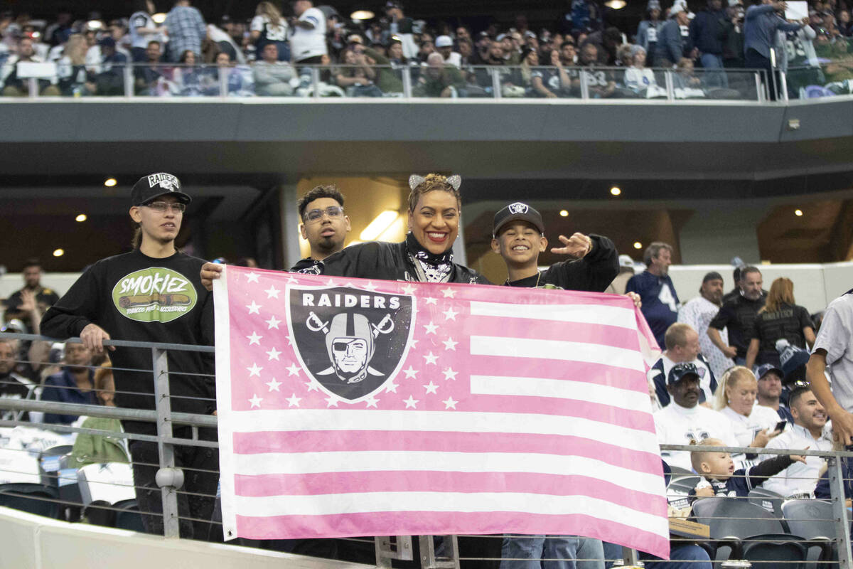 Raiders fans hold up a flag before an NFL football game against the Dallas Cowboys on Thursday, ...