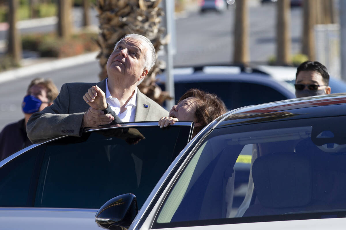 Gov. Steve Sisolak comforts a grieving family member as balloons are released during a vigil to ...