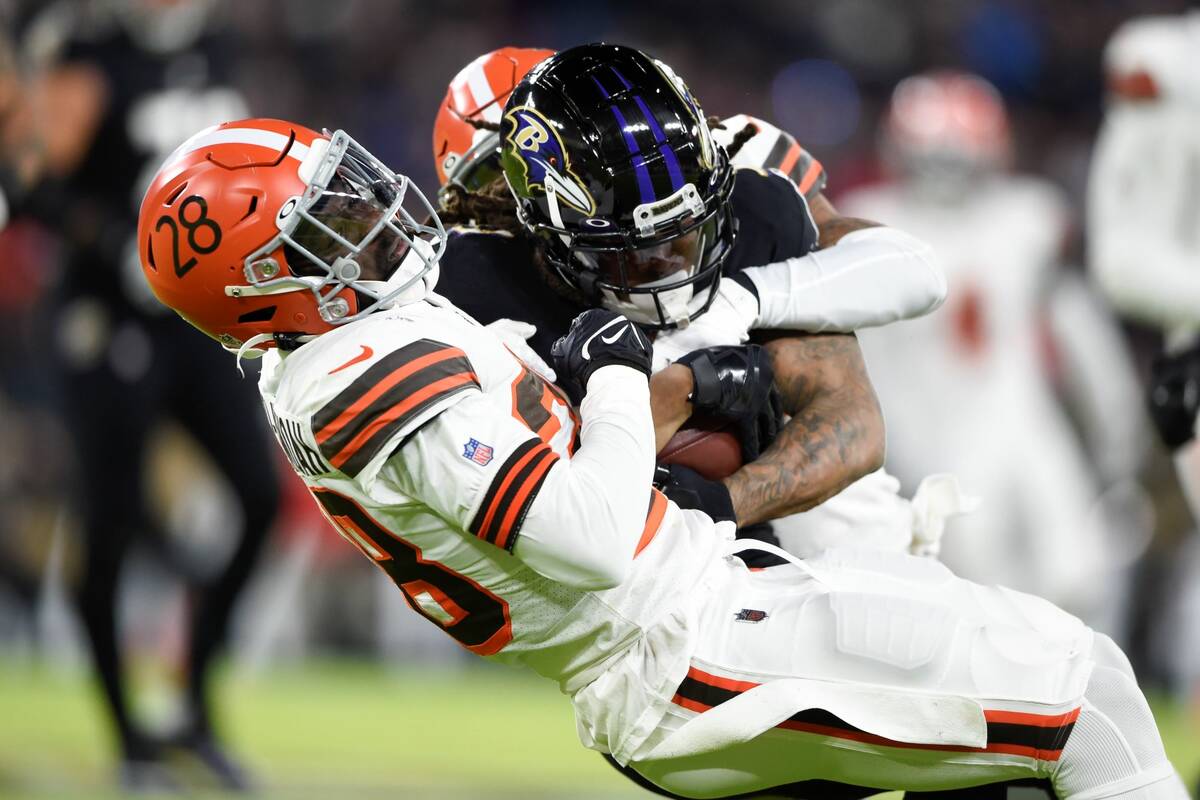 Baltimore Ravens running back Devonta Freeman, center, is tackled by Cleveland Browns outside l ...