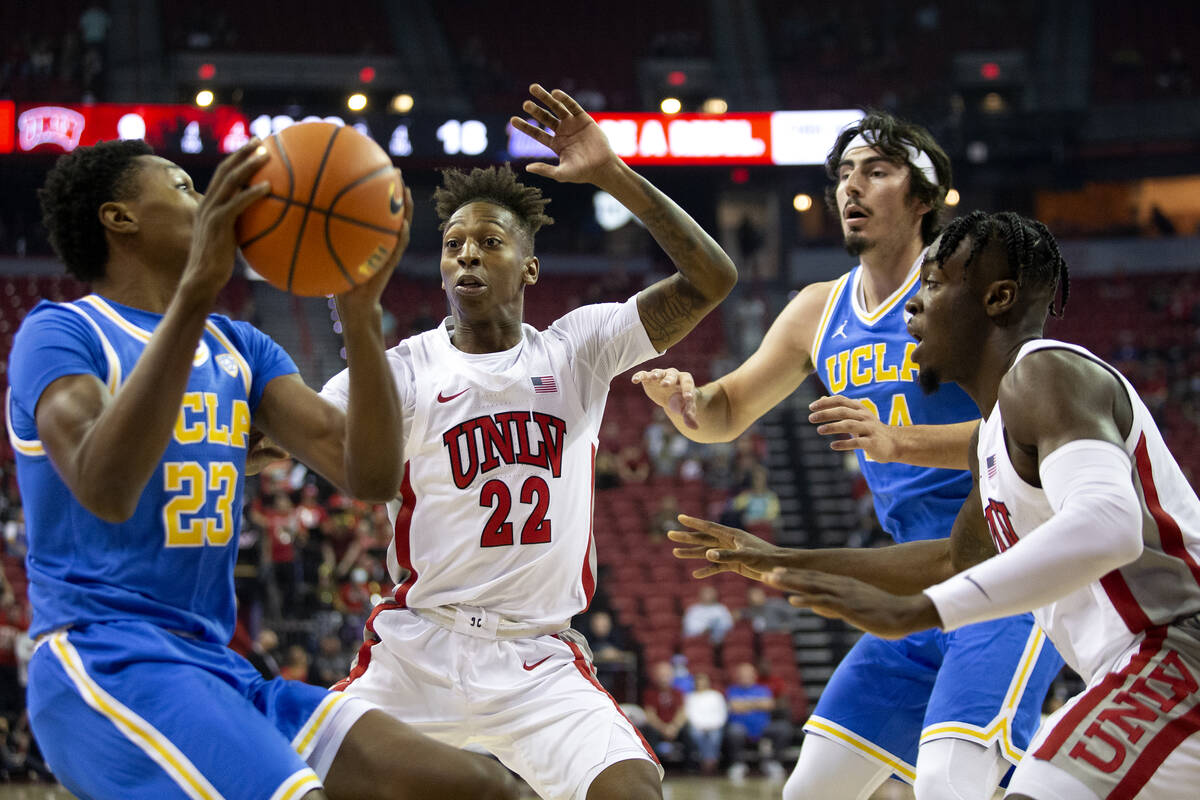 UCLA Bruins guard Peyton Watson (23) looks to pass while UNLV Rebels guard Josh Baker (22) and ...