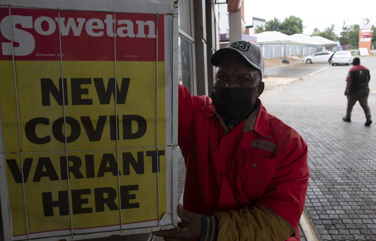 A petrol attendant stands next to a newspaper headline in Pretoria, South Africa, Saturday, Nov ...