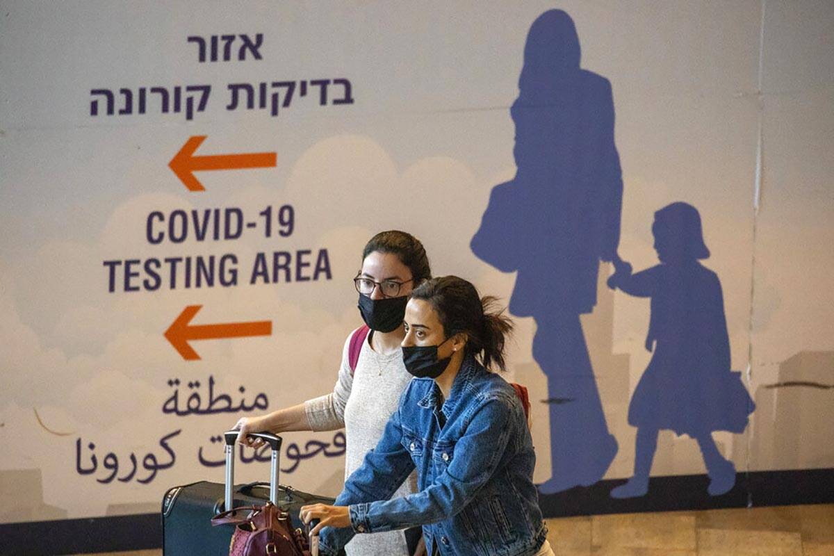 Travelers wearing protective face masks arrive at Ben Gurion Airport near Tel Aviv, Israel, Sun ...