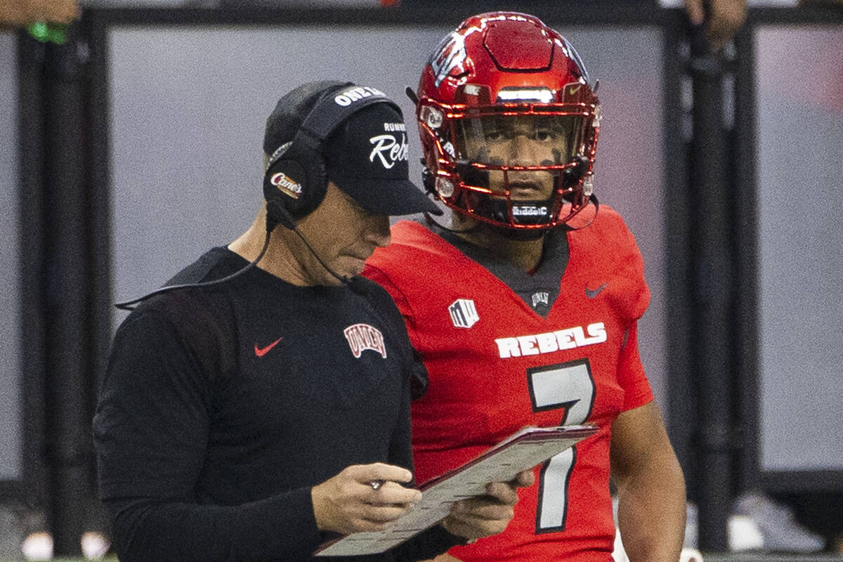 UNLV Rebels head coach Marcus Arroyo checks his game script as quarterback Cameron Friel (7) an ...