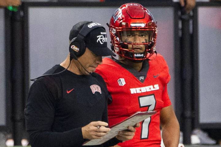 UNLV Rebels head coach Marcus Arroyo checks his game script as quarterback Cameron Friel (7) an ...