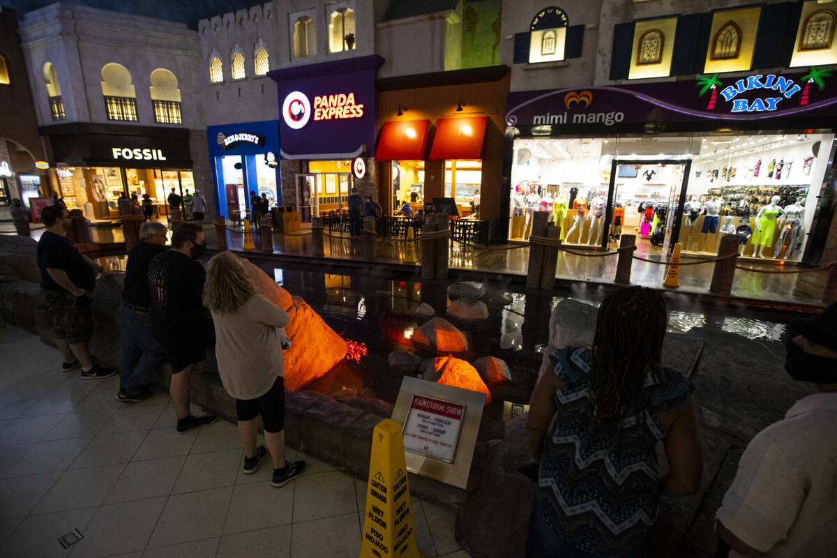 People watch the rainstorm show as signs encourage them to toss coins for charity at the Mirac ...