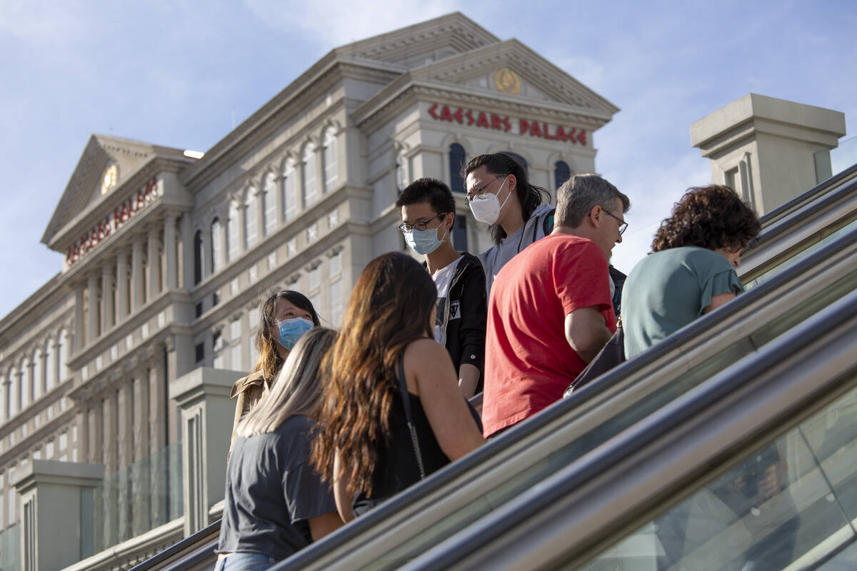 Visitors to the Las Vegas Strip ride escalators with Caesars Palace in the background on Friday ...