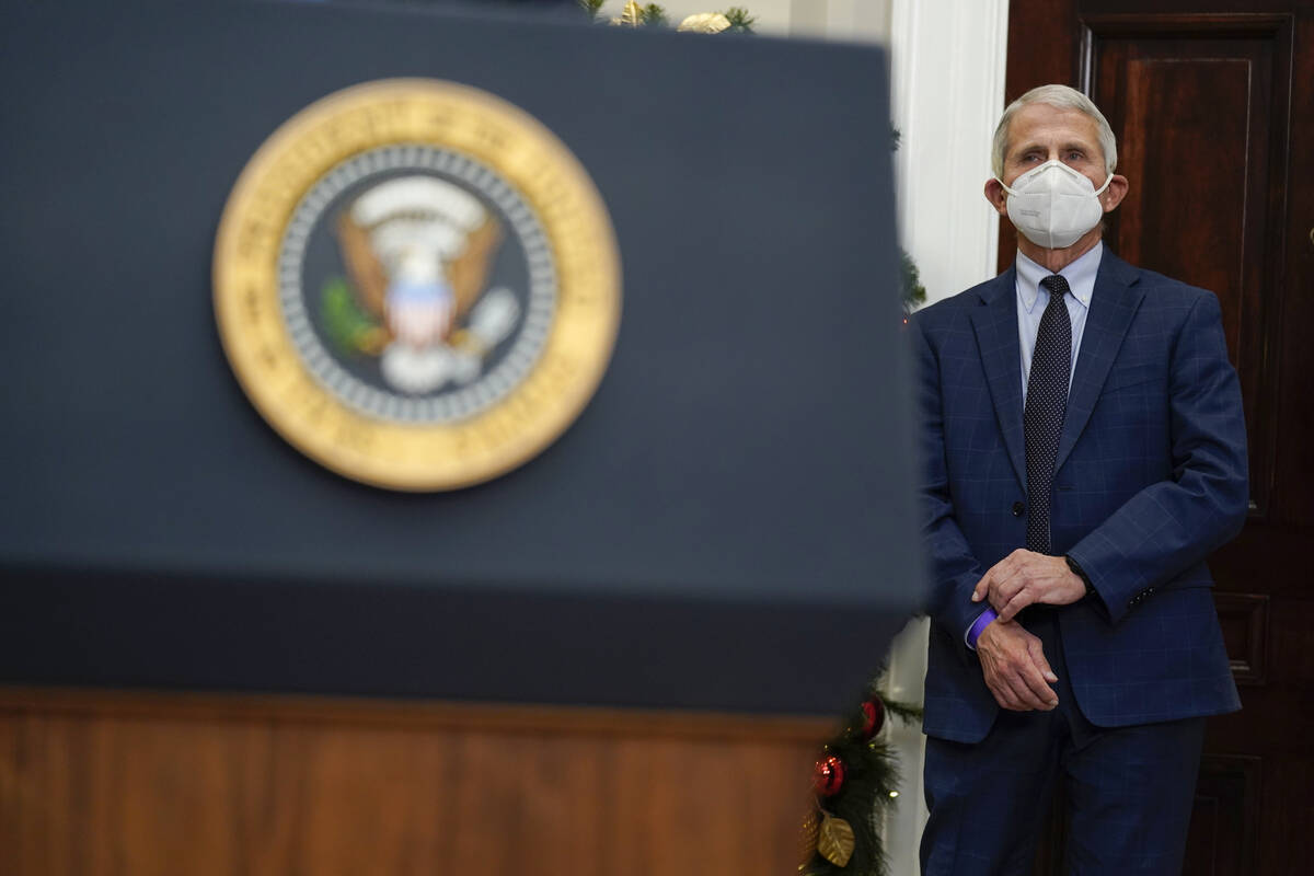 Dr. Anthony Fauci, director of the National Institute of Allergy listens as President Joe Biden ...