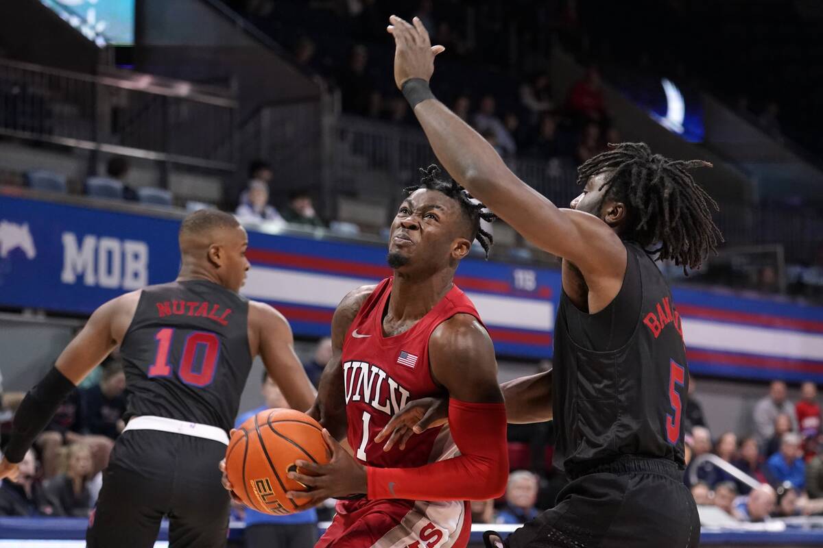 UNLV guard Michael Nuga (1) drives to the basket for a shot as SMU's Zach Nutall (10) and Emman ...