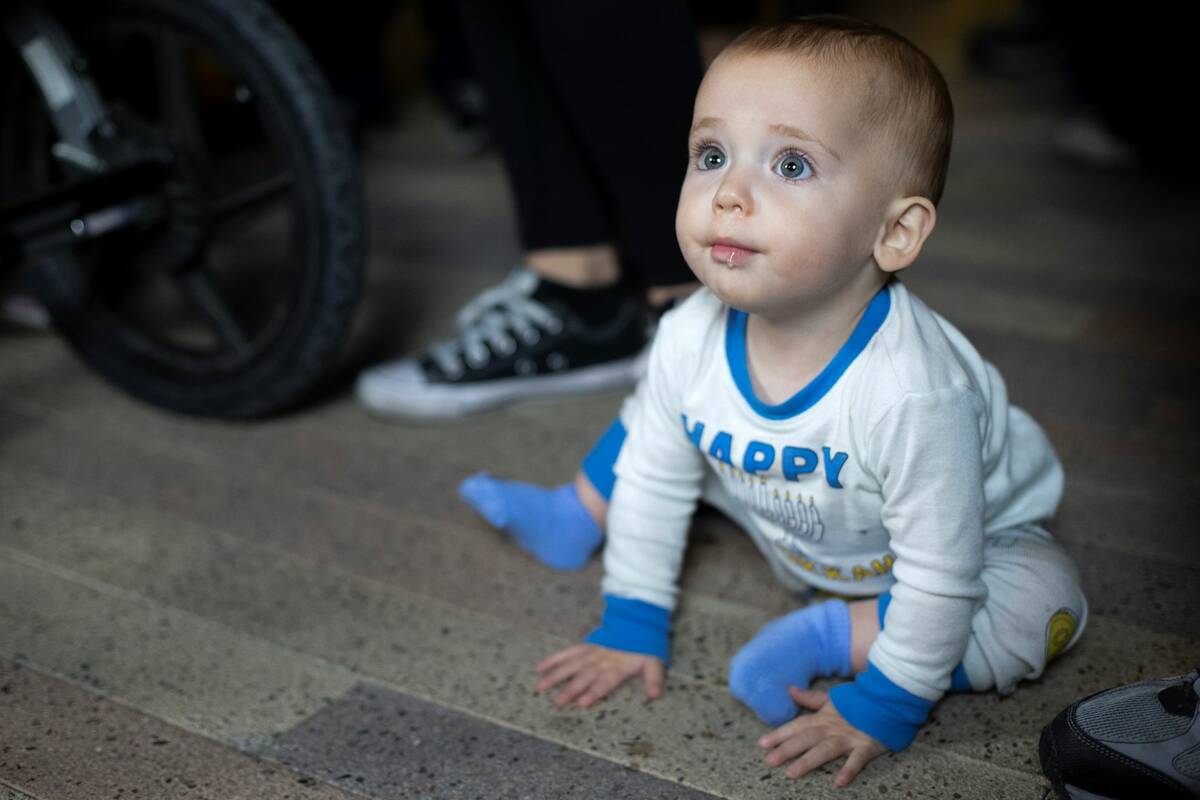 Sadie Shlisky, 11 months, watches as the menorah is lit for the fourth night of Hanukkah celebr ...