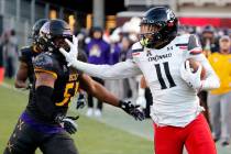 Cincinnati's Leonard Taylor (11) stiff arms East Carolina's Aaron Ramseur (51) during the first ...