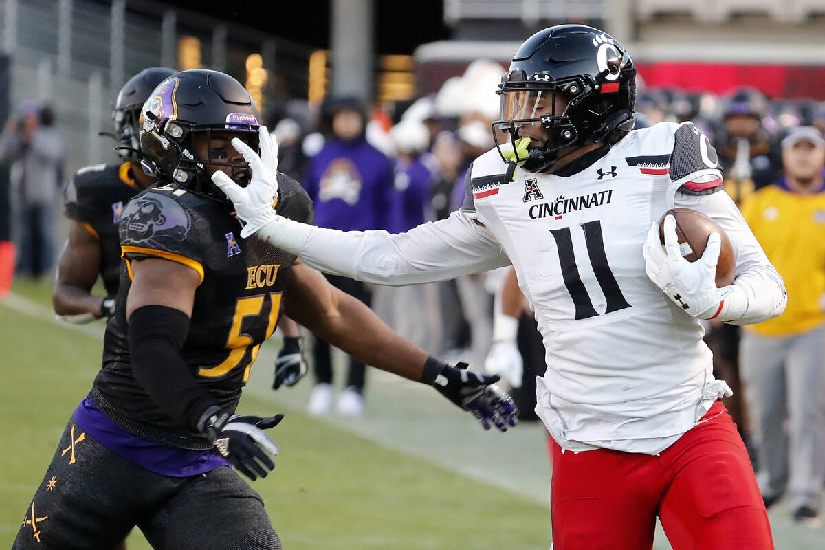 Cincinnati's Leonard Taylor (11) stiff arms East Carolina's Aaron Ramseur (51) during the first ...